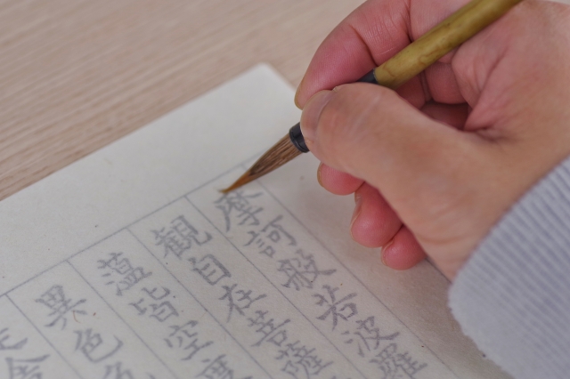 毛筆で写経を書いている手元のイメージ