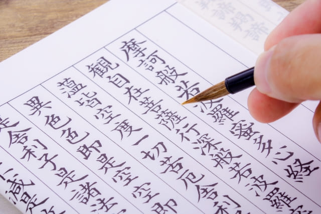 写経用紙に毛筆で丁寧に文字を書く手元