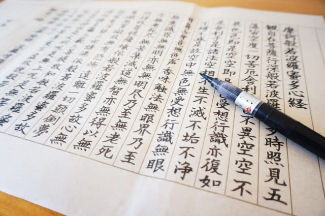 机に向かって写経をしている様子のイメージ